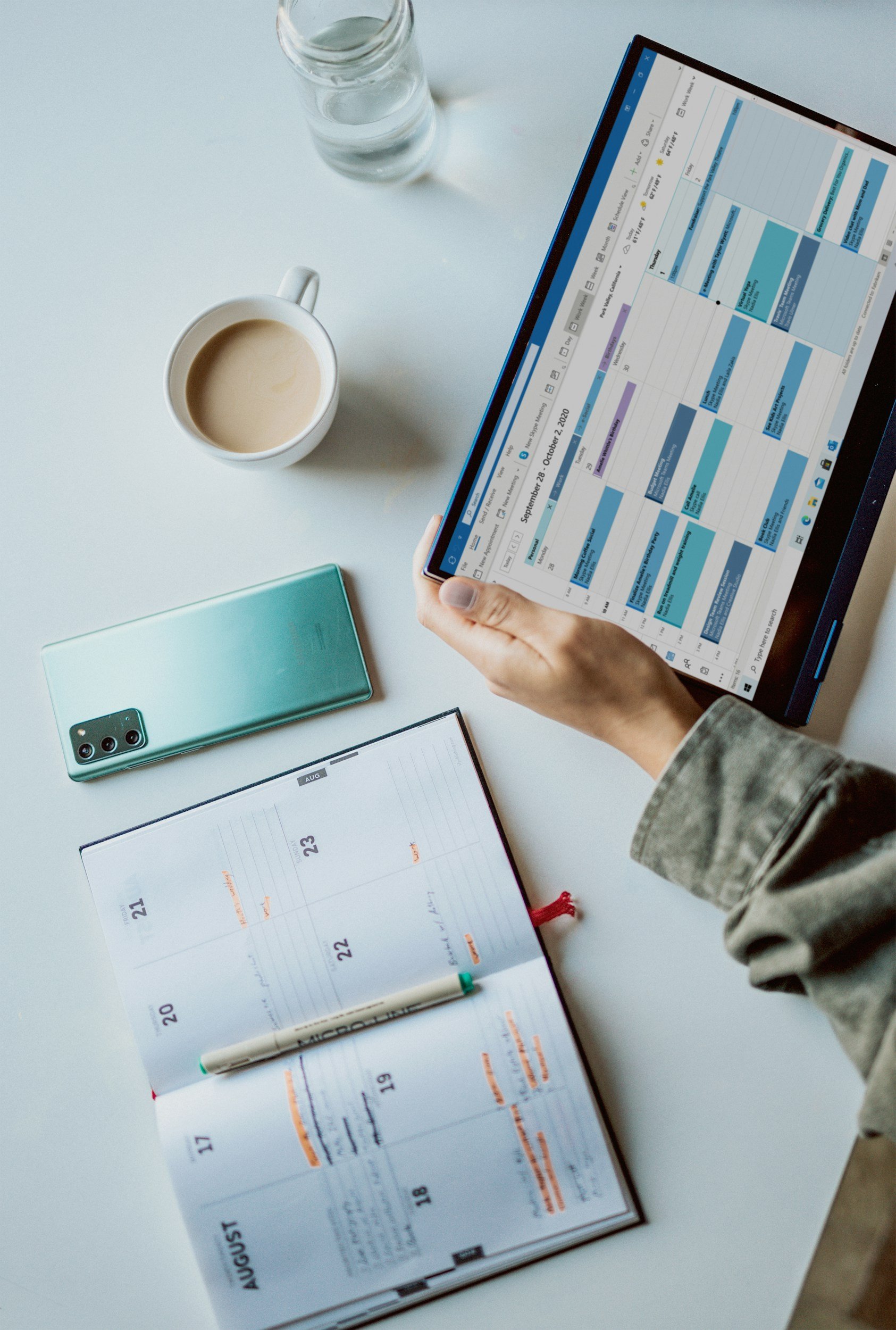 Tablet displaying a calendar beside a planner and coffee